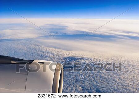 Stock Image - Plane flying over clouds. Fotosearch