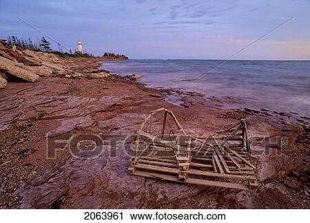 Stock Image - Point Prim Lighthouse And Old Lobster Trap, Sunset, Prince Edward Island, Canada. Fotosearch
