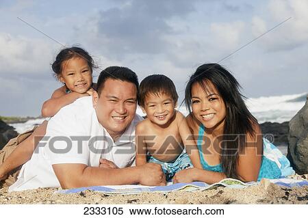 Stock Photography - Portrait of a family laying on a blanket on the beach; Honolulu oahu hawaii united states of america. Fotosearch