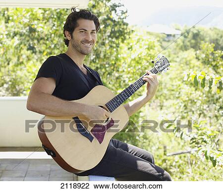 Portrait Of A Man Playing His Guitar Sitting On The Ledge Of A Balcony; Wailua Kauai Hawaii United States Of America View Large Photo Image Stock Image - Portrait Of A Man Playing His Guitar Sitting On The Ledge Of A Balcony; Wailua Kauai Hawaii United States Of America. Fotosearch