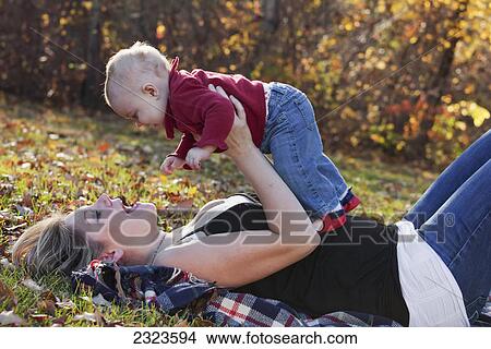 Picture - Portrait of a mother playing with her baby daughter in a park in autumn; Edmonton alberta canada. Fotosearch