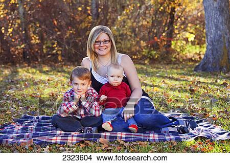 Portrait of a mother with her young son and baby daughter in a park in autumn; Edmonton alberta canada View Large Photo Image Picture - Portrait of a mother with her young son and baby daughter in a park in autumn; Edmonton alberta canada. Fotosearch