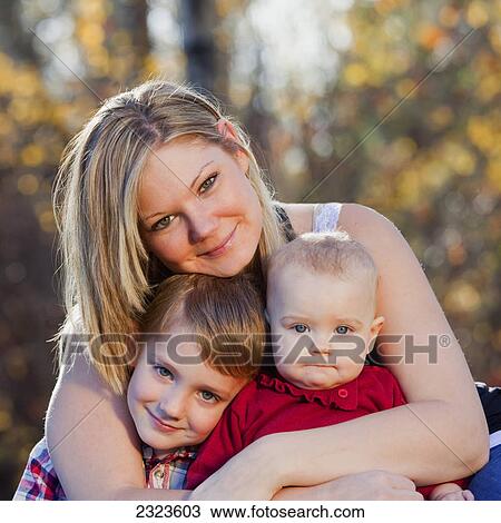 Stock Image - Portrait of a mother with her young son and baby daughter in a park in autumn; Edmonton alberta canada. Fotosearch
