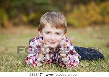 Portrait of a young boy laying on the grass in autumn; Edmonton alberta canada View Large Photo Image Stock Image - Portrait of a young boy laying on the grass in autumn; Edmonton alberta canada. Fotosearch