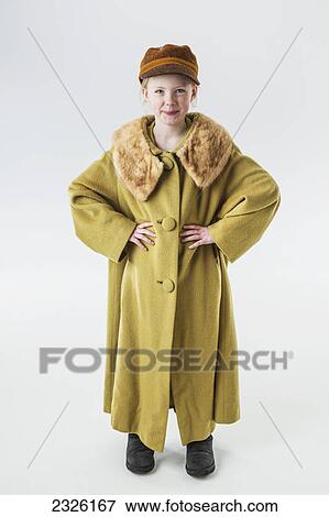 Stock Photo - Portrait of a young girl dressed in a grown up oversized coat on a white background; Anchorage alaska united states of america. Fotosearch