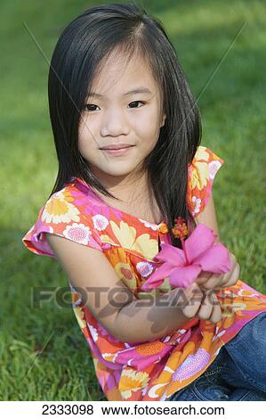Portrait of a young girl holding a pink tropical flower; Honolulu oahu hawaii united states of america View Large Photo Image Stock Photo - Portrait of a young girl holding a pink tropical flower; Honolulu oahu hawaii united states of america. Fotosearch