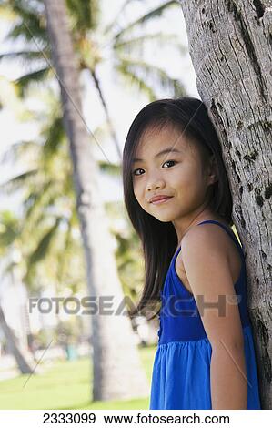 Portrait of a young girl leaning against the trunk of a tree; Honolulu oahu hawaii united states of america View Large Photo Image Stock Photo - Portrait of a young girl leaning against the trunk of a tree; Honolulu oahu hawaii united states of america. Fotosearch