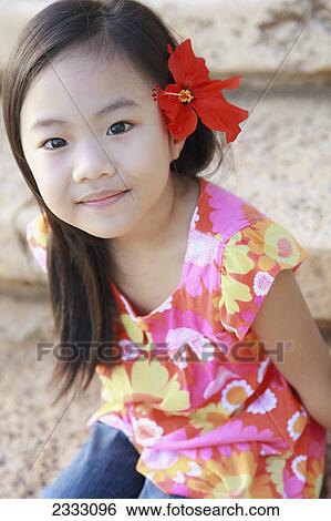 Stock Photograph - Portrait of a young girl with a red tropical flower in her hair; Honolulu oahu hawaii united states of america. Fotosearch