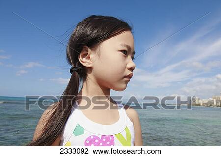 Stock Image - Portrait of a young girl with the buildings along the coastline in the distance; Honolulu oahu hawaii united states of america. Fotosearch