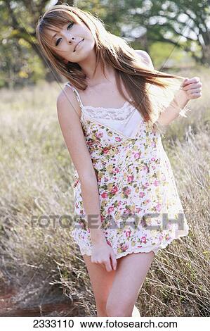 Stock Image - Portrait of a young woman with long hair in the long grass; Honolulu oahu hawaii united states of america. Fotosearch