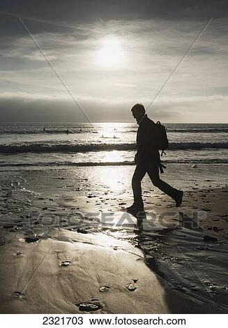 Stock Image - Silhouette Of A Man Walking On A Beach; Tarifa Cadiz Andalusia Spain. Fotosearch