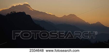 Silhouette of a mountainous landscape with a glowing sky behind it at sunset; Poon Hill, Annapurna, Nepal View Large Photo Image Stock Photo - Silhouette of a mountainous landscape with a glowing sky behind it at sunset; Poon Hill, Annapurna, Nepal. Fotosearch