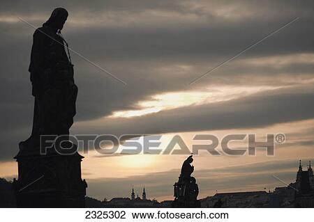 Stock Image - Silhouette of statues and buildings at sunset; Prague czech republic. Fotosearch