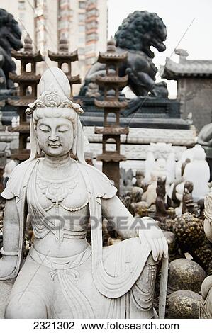 Stock Image - Statuary Including Buddhist Figure And Chinese Lion; Beijing China. Fotosearch