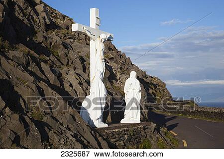 Stock Photo - Statue of jesus christ on the cross with two women at the foot of the cross on the side of the road; County kerry ireland. Fotosearch