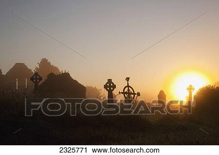 Stock Image - Sunrise at aghadoe heights graveyard with silhouetted tombstones; Killarney county kerry ireland. Fotosearch