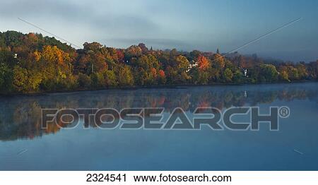 Stock Image - Sunrise breaks through the fog on the kennebec river; Gardiner maine united states of america. Fotosearch