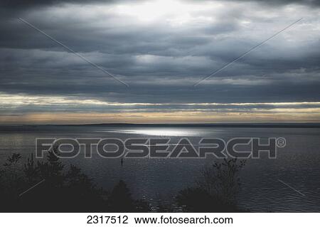 Stock Image - Sunrise Piercing Through Clouds And Lighting The St. Lawrence Waters; St. Simeon Quebec Canada. Fotosearch