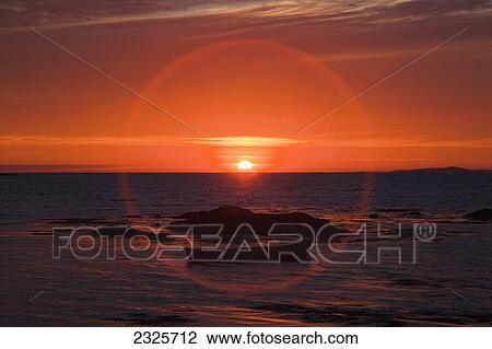 Stock Image - Sunset over mannin bay in a circular glare; County galway ireland. Fotosearch