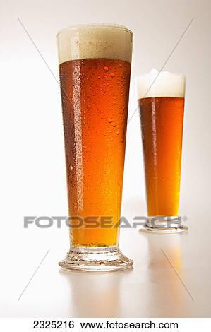 Stock Photograph - Tall glasses of cold beer with foam on top. Fotosearch
