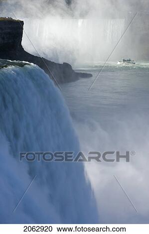 Stock Image - The American Falls With Horseshoe Falls And The Maid Of The Mist In The Background - Niagara Falls, New York, Usa. Fotosearch