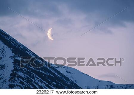 The crescent moon sets above the sentinal range along the alaska highway muncho lake provincial park northern canadian rockies; British columbia canada View Large Photo Image Stock Photo - The crescent moon sets above the sentinal range along the alaska highway muncho lake provincial park northern canadian rockies; British columbia canada. Fotosearch