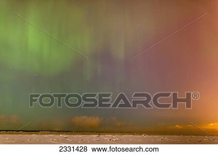 Stock Photo - The northern lights dance in the night sky above knik arm in this view from the tony knowles coastal trail in winter; Anchorage alaska united states of america. Fotosearch