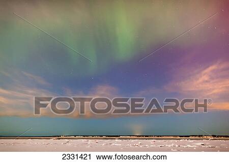 Stock Image - The northern lights in the night sky above knik arm from the tony knowles coastal trail in winter; Anchorage alaska united states of america. Fotosearch