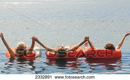 Three people floating on the ocean in orange inflatable tubes; Waikiki oahu hawaii united states of america View Large Photo Image Stock Image - Three people floating on the ocean in orange inflatable tubes; Waikiki oahu hawaii united states of america. Fotosearch