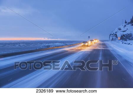 Traffic driving on the seward highway during a snowstorm at twilight in winter beluga point; Anchorage alaska united states of america View Large Photo Image Stock Photo - Traffic driving on the seward highway during a snowstorm at twilight in winter beluga point; Anchorage alaska united states of america. Fotosearch