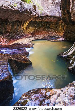 Stock Image - Utah, Zion National Park, Subway Slot Canyon, Stunning cavern and pool of water.. Fotosearch