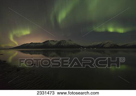 Stock Image - View of the aurora borealis (northern lights) dancing above the chugach mountains and reflecting in the waters of turnagain arm kenai peninsula; Alaska united states of america. Fotosearch