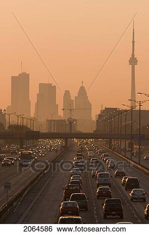 Stock Photograph - View Of Toronto Skyline From Above Queen Elizabeth Way Highway During Start Of Rush Hour Traffic, Toronto, Ontario, Canada.. Fotosearch