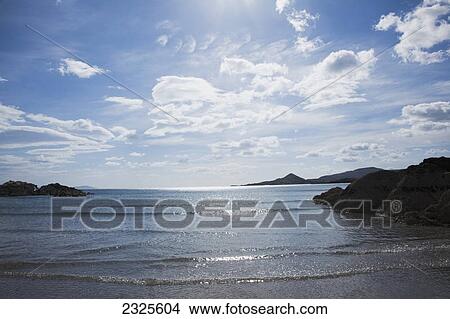 Waves rolling up onto the shore with sunlight reflecting on the water; County kerry ireland View Large Photo Image Picture - Waves rolling up onto the shore with sunlight reflecting on the water; County kerry ireland. Fotosearch