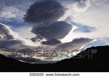 Stock Image - Wind sculpted cumulus clouds in sky above divide mountain and toklat river denali national park; Alaska united states of america. Fotosearch