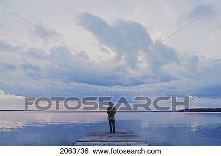 Stock Photograph - Woman On Public Dock Clear Lake; Canada, Manitoba, Riding Mountain National Park. Fotosearch