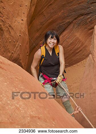 Stock Photograph - Woman rappelling into a slot canyon; Hanksville utah united states of america. Fotosearch