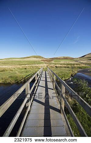 Wooden Boardwalk With Railing Over A River With A Blue Sky; Cheviot Hills Northumberland England View Large Photo Image Stock Photography - Wooden Boardwalk With Railing Over A River With A Blue Sky; Cheviot Hills Northumberland England. Fotosearch