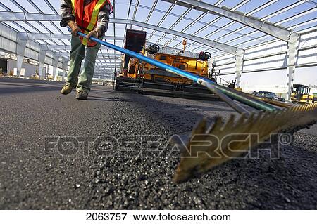 Stock Photo - Worker Leveling Asphalt With A Rake; Canada, Ontario, Hamilton (Composting Facility). Fotosearch