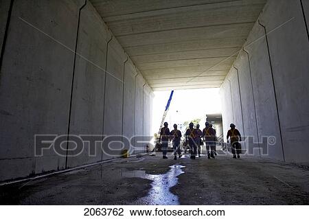 Stock Image - Workers Walking Down A Concrete Tunnel; Canada, Ontario, Hamilton (Composting Facility). Fotosearch