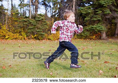Stock Photo - Young boy running in a park in autumn; Edmonton alberta canada. Fotosearch