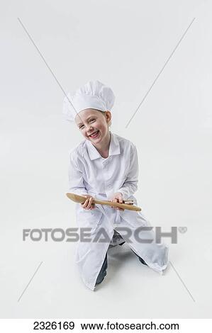 Young girl wearing a white chef's hat and apron and holding a wooden spoon; Anchorage alaska united states of america View Large Photo Image Stock Photo - Young girl wearing a white chef's hat and apron and holding a wooden spoon; Anchorage alaska united states of america. Fotosearch