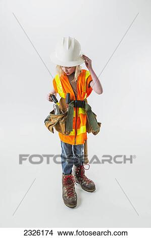 Young girl wearing oversized construction clothes and hard hat pulling a screwdriver out of her tool belt; Anchorage alaska united states of america View Large Photo Image Picture - Young girl wearing oversized construction clothes and hard hat pulling a screwdriver out of her tool belt; Anchorage alaska united states of america. Fotosearch