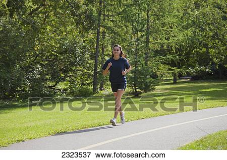 Young woman jogging on a pathway in a park; Edmonton alberta canada View Large Photo Image Stock Photo - Young woman jogging on a pathway in a park; Edmonton alberta canada. Fotosearch