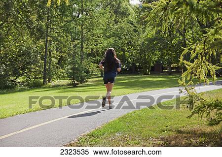 Stock Photography - Young woman jogging on a pathway in a park; Edmonton alberta canada. Fotosearch