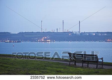 A bench and path along the water's edge with boats illuminated by lights in the river View Large Photo Image Stock Image - A bench and path along the water's edge with boats illuminated by lights in the river. Fotosearch