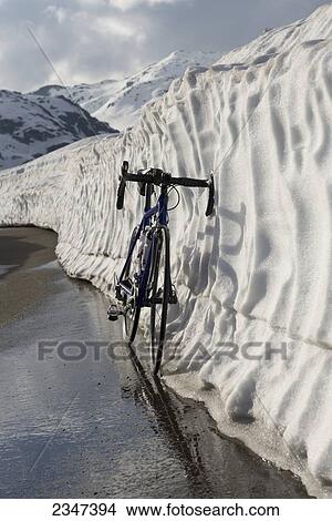 A bicycle leaning against a wall of snow in a mountain pass; San Gottardo, Uri, Switzerland View Large Photo Image Picture - A bicycle leaning against a wall of snow in a mountain pass; San Gottardo, Uri, Switzerland. Fotosearch