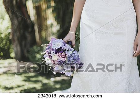 Stock Photo - A bride holding a colourful bouquet; Pemberton, British Columbia, Canada. Fotosearch