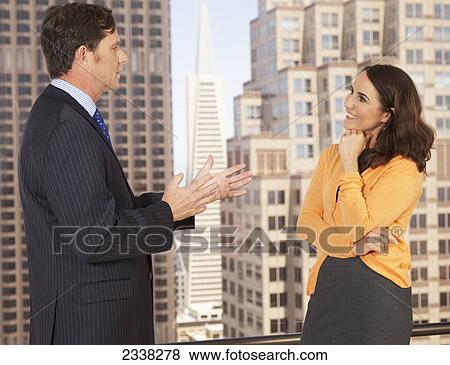 Stock Photo - A businessman and businesswoman having a discussion; Portola Valley, California, United States of America. Fotosearch