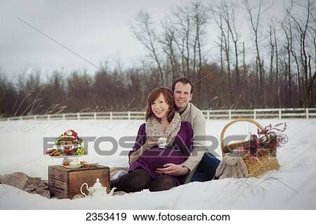 Stock Photo - A couple having a winter picnic during pregnancy; Edmonton, Alberta, Canada. Fotosearch